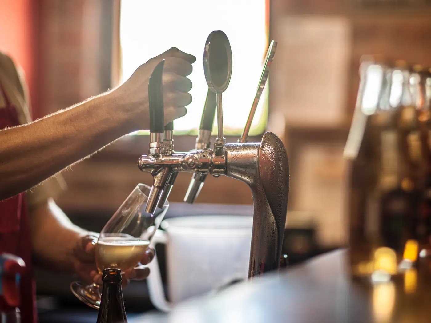 A bartender pulling a draft beer at a pub tap